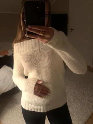 Offshoulder stickad tröja Gina Tricot - Supermysig offshoulder stickad tröja från Gina Tricot i krämvit färg. Tröjan har bred ribbad kant upptill och vid ärmslut, lång ärm och en loose fit som ger en chill vibe. Perfekt att styla med jeans eller kjol för en snygg look.