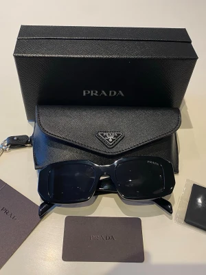 PRADA Sunglasses SPR 17W-F Black  - Stunning PRADA SPR 17W-F sunglasses, brand new without tags for a chic and sophisticated look.  📦Livraison : fast and careful ✨Condition: 10/10 - New without tags, never worn 🎨Color: Black 📏Size: One size Don't hesitate to send me a message if you have any questions about the item 📩