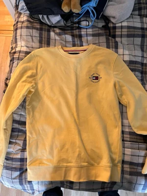 Gul sweatshirt från Tommy Hilfiger - Gul sweatshirt från Tommy Hilfiger i ekologisk bomull. Tröjan har rund hals, diskret logga på bröstet och ärmarna samt ribbade muddar. Den är aldrig använd, så finns inga defekter på tröjan. Passar dig som har m och s. Skriv vid frågor!!!
