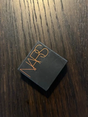 NARS Laguna Bronzer mini - Säljer en ikonisk bronzer från NARS i färgen Laguna. Kommer i en kompakt svart dosa med spegel och har en varm, gyllenbrun ton med lätt skimmer. Perfekt för att skapa solkysst look och contour. Smidig att ha med i väskan.