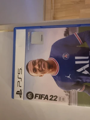 FIFA 22 PS5 - FIFA 22 till PlayStation 5 i mycket gott skick. Komplett med fodral och skiva. Upplev realistisk fotboll med Hypermotion-teknologi och spel i Ultra HD. Perfekt för fotbollsälskare och PS5-spelare.
