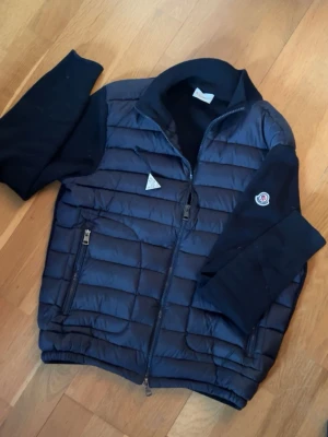 Moncler Cardigan - Säljs då den inte används mer. Sömmen vid höger armhåla har spruckit ungefär 3 cm. Lätt att laga med tråd o nål. Förutom det är jackan i väldigt fint skick. Storlek S/1. Skriv gärna vid funderingar!😊