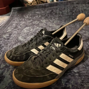Adidas Spezial svarta sneakers mocka - Säljer ett par Adidas Spezial sneakers i svart mocka med vita detaljer och klassiska tre ränder på sidan. Skorna har gummisula i brunt och snörning framtill. Perfekta för dig som gillar retrostil och streetwear. Helt okej skick 