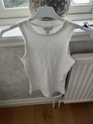 Vit ribbad linnetopp från AWARE - Säljer en vit ribbad linnetopp från AWARE i storlek XS. Toppen är ärmlös med rund halsringning och har en clean, enkel look som passar perfekt till sommaren. Materialet är mjukt och stretchigt för en bekväm passform. Aldrig använt!