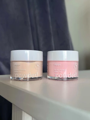 Dippulver från Dippi - ’Sugar Rush’ & ’Peachy’ - Två burkar dip-pulver från Dippi. Sugar Rush (ljus beige/guk) och Peachy (ljusrosa/aprikos). Vegansk och HEMA-fri formula, 15 ml per burk.  Perfekt för att skapa snygga naglar! Båda burkarna är använda en gång var.