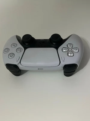 PlayStation 5 Kontroll - DualSense trådlös handkontroll till PlayStation 5 i vitt och svart. Kontrollen är i gott skick med minimalt synligt slitage. Ergonomisk design, adaptiva triggers och inbyggd mikrofon för bästa spelupplevelse.
