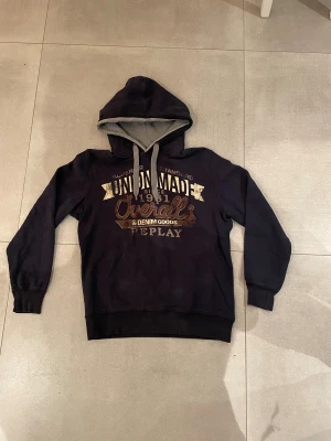 Replay hoodie - Tja! Säljer en riktigt snygg mörkblå hoodie från replay med ett snyggt tryck framtill och är lite ”slitet” för design då såklart, skicket är 10/10 och inga defekter, lite för stor på killen på bilden som är 185 cm lång och han är även ganska smal storleken är L men sitter lite typ mellan M och L men hör av dig vid minsta fundering eller fråga!!!🤗mvh EM_resel
