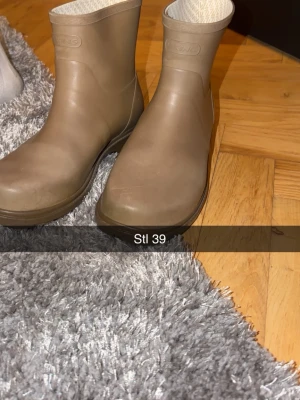 Beige stövlar från Viking stl 39 - Säljer ett par beige stövlar från Viking i storlek 39. De har en rund tå och är tillverkade i syntetmaterial med mönstrat innerfoder. Perfekta för regniga dagar och har en platt sula för skön komfort.
