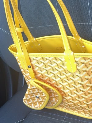 Gul handväska  - Säljer en snygg gul handväska med klassiskt rutig mönster och matchande liten plånbok. Väskan har två handtag och detaljer i gult skinn. Perfekt storlek för det viktigaste och riktigt trendig design.