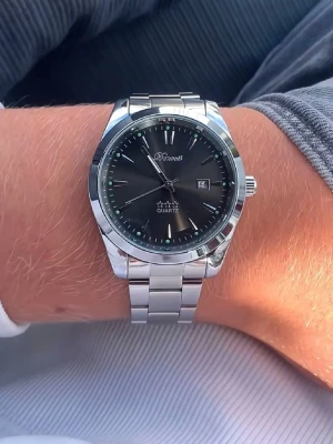 Svart klockan från Doventi  - Stilren herrklocka från Doventi med blå urtavla och silverfärgat armband i metall. Klockan har datumvisning och klassisk rund form med tydliga indexmarkeringar. Perfekt accessoar för dig som gillar en clean och modern look.