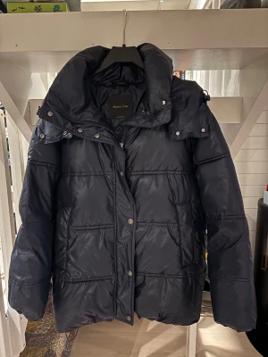 pufferjacka från Massimo Dutti - Snygg pufferjacka från Massimo Dutti med stor huva och dragkedja framtill. Köpte för något år sen och är knappt använd. Storlek XS men är ganska stor i storlek o sitter som en S skulle jag säga 