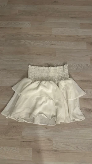 Vit volangkjol från Chelsea XS - Supersöt vit kortkjol från Chelsea i storlek XS. Kjolen har bred smock i midjan och dubbla lager med volanger. Köpt i Göteborg för ca 1 år sen och knappast använd. 