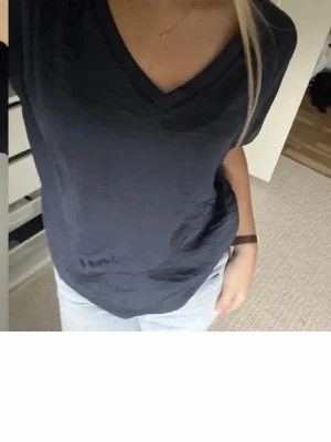 Mörkblå v-ringad t-shirt - Snygg mörkblå t-shirt med v-ringad hals och korta ärmar. T-shirten har en loose passform och är tillverkad i mjuk bomull som känns skön mot huden. Perfekt att matcha med jeans eller kjol för en chill och stilren look.