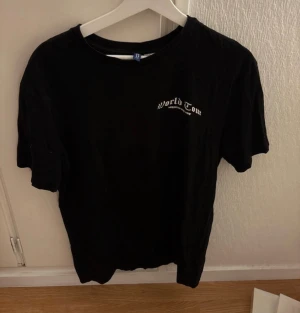Svart World Tour t-shirt från H&M Divided - Svart t-shirt från H&M Divided i storlek M med trycket 'World Tour' på bröstet och en stor grafisk print på ryggen med basketmotiv och stadnamn. Köpt för något år sedan men knappt använd