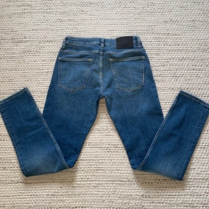Blå jeans från Neuw - Snygga blå jeans från Neuw och svarta läderpatch med logga bak. Modellen är slim/straight i storlek 29/32. tillverkade i mjukt jeanstyg som sitter skönt. Perfekta för dig som gillar stilrena och moderna jeans. Nypris:1400.   använda en gång, säljer då de är för långa för mig.