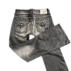 Bootcut jeans från guess - Lågmidjade bootcut jeans ifrån guess, snygga detaljer på fickorna och stenar. Midja: 89cm Innerbenslängd: 86/87cm. Lite slitna längst ner annars bra skick