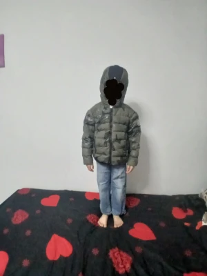 Moncler Jacka för barn. Glöm och camouflage  - Säljer en grön dunjacka från Moncler med camouflagemönster och svart detalj på huvan. Jackan har lång ärm, dragkedja och Moncler-logga på ärmen. Perfekt för kalla dagar och har en schysst oversized look.