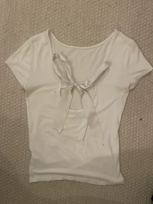 T shirt med rosett - Vit topp med band vid ryggen så man kan knyta och göra en rosett.