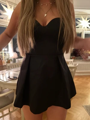 Bandau klänning  - Säljer en svart axelbandslös kortklänning med sweetheart-urringning och utsvängd kjol. 