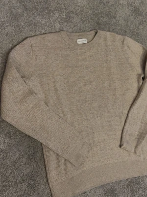 Beige stickad tröja These Glory Days - Säljer en beige stickad tröja från These Glory Days i storlek XL. Tröjan har rund hals, ribbade muddar och långärmad passform. Perfekt för dig som gillar enkel och stilren design med mjukt material.