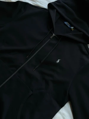 Ralph Lauren - Säljer en Polo Ralph Lauren i storlek XXL med mörkgrå logga som jag fick som födelsedagspresent för ett tag sedan. Koftan är för stor och har bara legat i mitt rum utan någon användning. Har bara provat koftan!