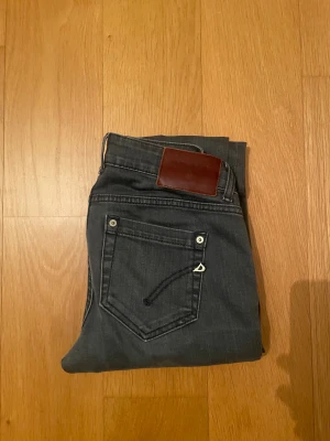 Dondup - Snygga mörkgrå jeans från Dobber med klassisk femficksdesign och raka ben. Jeansen har en brun läderpatch bak i midjan och diskreta sömmar på bakfickorna. Materialet är mjukt och stretchigt jeans-tyg som sitter skönt hela dagen.
