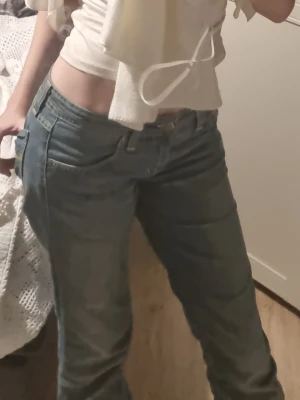 Blå bootcut jeans från Denimbirds - Säljer ett par superlågmidjade blå bootcut jeans från Denimbirds i storlek 31/34. De har inga tecken på användning och passar perfekt på mig som är 172 cm.Jeansen har klassisk femficksdesign, snygga slitningar och kontrastsömmar i gult. Modellen har låg midja och är tillverkad i mjukt denimtyg som sitter skönt hela dagen.