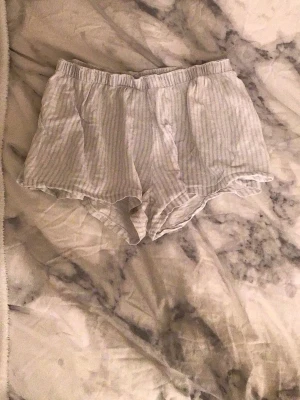 Super sköna pyjamas shorts - Säljer ett par superlätta och luftiga shorts med ljusgrå och vita ränder. De har elastisk midja och är tillverkade i mjuk bomull, perfekta för varma dagar. Passformen är loose och de har en avslappnad vibe.