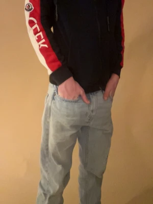 Moncler hoodie  - Säljer min Moncler hoodie i bra skick (finns en liten defekt vid bredvid dragkedjan men det är bara några trådar som sticker ut, se bild i annonsen) Axelbredd- 45cm, längd - 60 cm, armlängd - 55 cm. Jag på bilden är 175 och väger 60 kg. Passar både S och XS