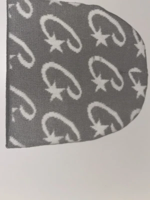 Cortez mössa - Säljer en grå stickad väst med vitt mönster av stjärnor och böjda linjer. Västen har en mjuk och skön känsla, perfekt för att addera lite extra stil till din outfit. Den är enkel att matcha och har en modern look.