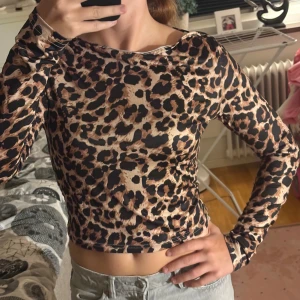 Leopardmönstrad långärmad topp - Säljer en snygg långärmad topp med leopardmönster i beige, brunt och svart. Modellen är croppad och har en tight passform med rund halsringning. Perfekt för dig som vill sticka ut lite extra. Aldrig använd jättefint skick