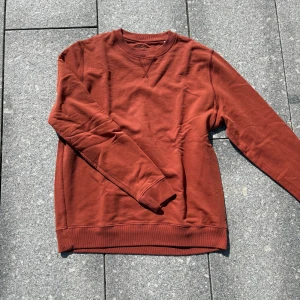 Rostbrun sweatshirt från Stenströms - Snygg rostbrun sweatshirt från Stenströms med broderad logga vid halsen och ärmslut. Tröjan har rund halsringning, ribbade muddar och klassisk relaxed fit. Perfekt för lager-på-lager och chill dagar. Tillverkad i mjuk bomull.