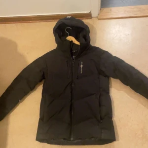 Svart dunjacka från Peak Performance - Säljer min Sail racing vinterjacka storlek 170. Det är i riktigt fint skick och bara använt ett fåtal gånger. Supervarm och skön, perfekt nu till vinter. Köpte 3000kr säljer 1800kr