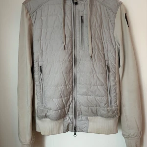 Parajumper Cardigan XS - Snygg ljusgrå jacka från Parajumper med luva. Jackan har ribbade muddar och är i bra skick. Tecken på användning finns.