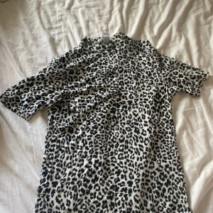 Leopard T-shirt - Snygg t-shirt från Amisu i leopardmönster med svart och vit färg. Modellen är klassisk med korta ärmar och rund hals. Perfekt för dig som vill sticka ut lite extra med ett djurmönster. Tillverkad i mjukt bomullsmaterial som känns skönt mot huden. Y2k 