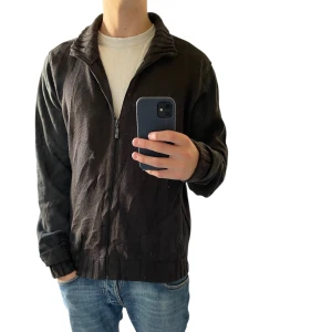 Svart stickad jacka från Puma XL - Svart jacka från Puma i storlek XL med stickad struktur på krage, muddar och nederkant. Jackan har dragkedja framtill och är tillverkad i en mix av stickat material och släta ärmar. Modellen år cirka  188 cm - 78 kg