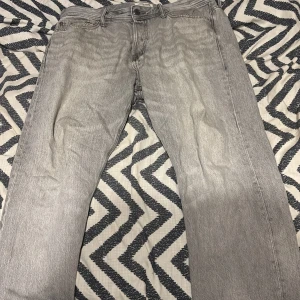 jack & jones jeans - Snygga grå jeans med rak passform och klassisk femficksdesign. Jeansen har en ljus tvätt och är perfekta för en avslappnad stil. Tillverkade i mjukt jeanstyg med dragkedja och knapp framtill.