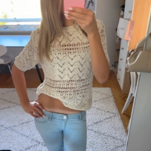 Stickad kortärmad tröja från Zara - Superfin stickad tröja från Zara i offwhite med korta ärmar och snyggt hålmönster. Tröjan är lite croppad och har rund halsringning. 