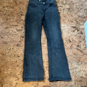 Svarta/gråa bootcut jeans från Lindex - Snygga svarta/gråa jeans från Lindex i modell Freja, storlek 140. Jeansen har klassisk femficksdesign, hög midja och bootcut-ben som ger en cool siluett. Tillverkade i mjukt denimtyg som är skönt att bära hela dagen.