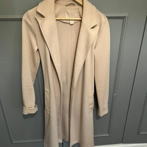 Medel lång beige kappa - Längre beige kappa från New yorker. Använd ett fåtals gånger bara. I storlek 34