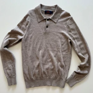 Beige pikétröja i kashmir från morris  - Snygg beige pikétröja från Brothers i mjuk ull. Klassisk krage, tre knappar framtill och långa ärmar. Perfekt för dig som gillar stilrena och tidlösa plagg med en modern touch.