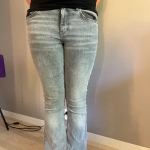 Grå bootcut jeans från Gina tricot - Snygga ljusgrå bootcut jeans från Gina tricot i storlek 36. Jeansen har vanliga fickor, normal passform och är tillverkade i mjukt denimtyg. Bra för dig som gillar mer bootcut.