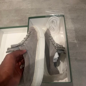 Grå mockasneakers från Diemme - Snygga grå sneakers från Diemme i mjuk mocka med vita, platta sulor och metallöglor för snörningen. Skorna har en stilren och clean look, perfekt för dig som gillar minimalistisk stil. Extra vita skosnören medföljer i kartongen.