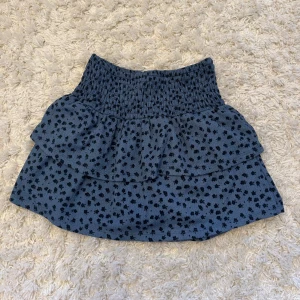Blå volangkjol med småblommigt från Zara - Supersöt blå kortkjol från Zara med små svarta blommor. Kjolen har inbyggda skjorts vilket är jätteskönt om man vill leka runt utan att oroa sig för att kjolen ska åka upp. Jag säljer denna kjolen för 200kr + frakt som kunden betalar, pris kan diskuteras.