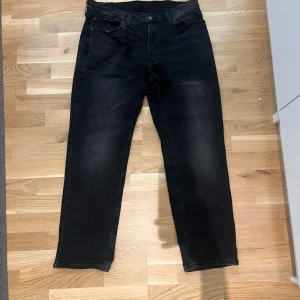 Svarta Levi's 541 jeans W36 L32 - Svarta jeans från Levi's modell 541 med klassisk femficksdesign och raka ben. Jeansen har en mörk tvätt och är tillverkade i slitstarkt denim med knapp och dragkedja i midjan. Perfekt för dig som gillar en clean och tidlös look.
