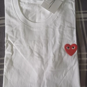 Vit t-shirt Comme des Garçons Play - Vit t-shirt från Comme des Garçons Play med rött hjärta med ögon broderat på bröstet. Tröjan är helt oanvänd, med alla tags kvar. Nypris: ~800. Storlek S. Tveka inte att höra av er med funderingar eller prisförslag!