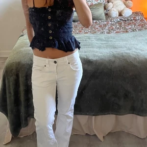 Vita jeans från Tommy Hilfiger - Säljer ett par vita jeans från Tommy Hilfiger med klassisk femficksdesign och guldigt logomärke bak i midjan. Byxorna har låg midja och raka ben, med små broderade Hilfiger-detaljer på fickorna. Väldigt lågmidjade och passar perfekt i längden för mig som är 158