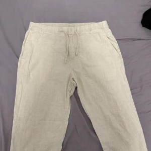 Beige linnebyxor från H&M med snörning - Snygga beige linnebyxor från H&M i regular fit. Byxorna har elastisk midja med snörning och sidfickor, perfekta för en chill och avslappnad stil. Lätta och luftiga, grymma till sommaren.