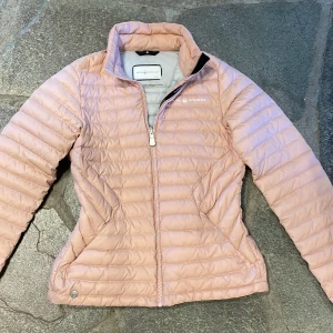 Ljusrosa pufferjacka från Sail Racing - Säljer en ljusrosa pufferjacka från Sail Racing i storlek medium. Jackan har quiltad design, dragkedja framtill och hög krage. Perfekt för kyliga dagar och riktigt snygg till jeans eller tights. Materialet är syntet och jackan är lätt och smidig att bära. 