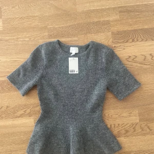 Grå ribbad topp - Superfin grå ribbad topp från H&M med korta ärmar. Toppen är aldrig använd och lappen sitter kvar!